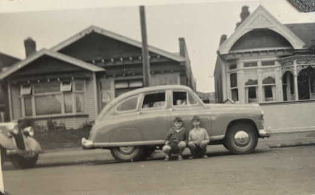 A 1950s black-and-white street photograph, faded